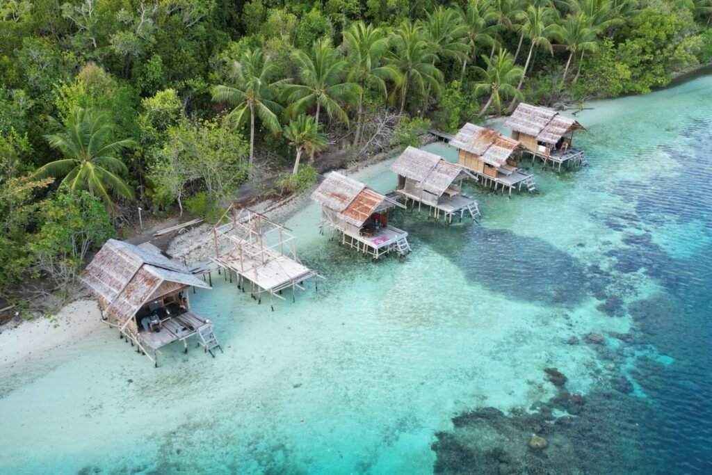 Stunning aerial shot of traditional huts along the tropical coast of Waigeo Barat, West Papua.