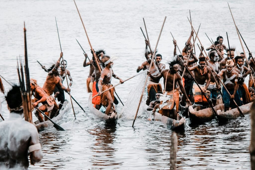 Indigenous tribes in Papua, Indonesia, engaged in a traditional canoe race on a serene water body.