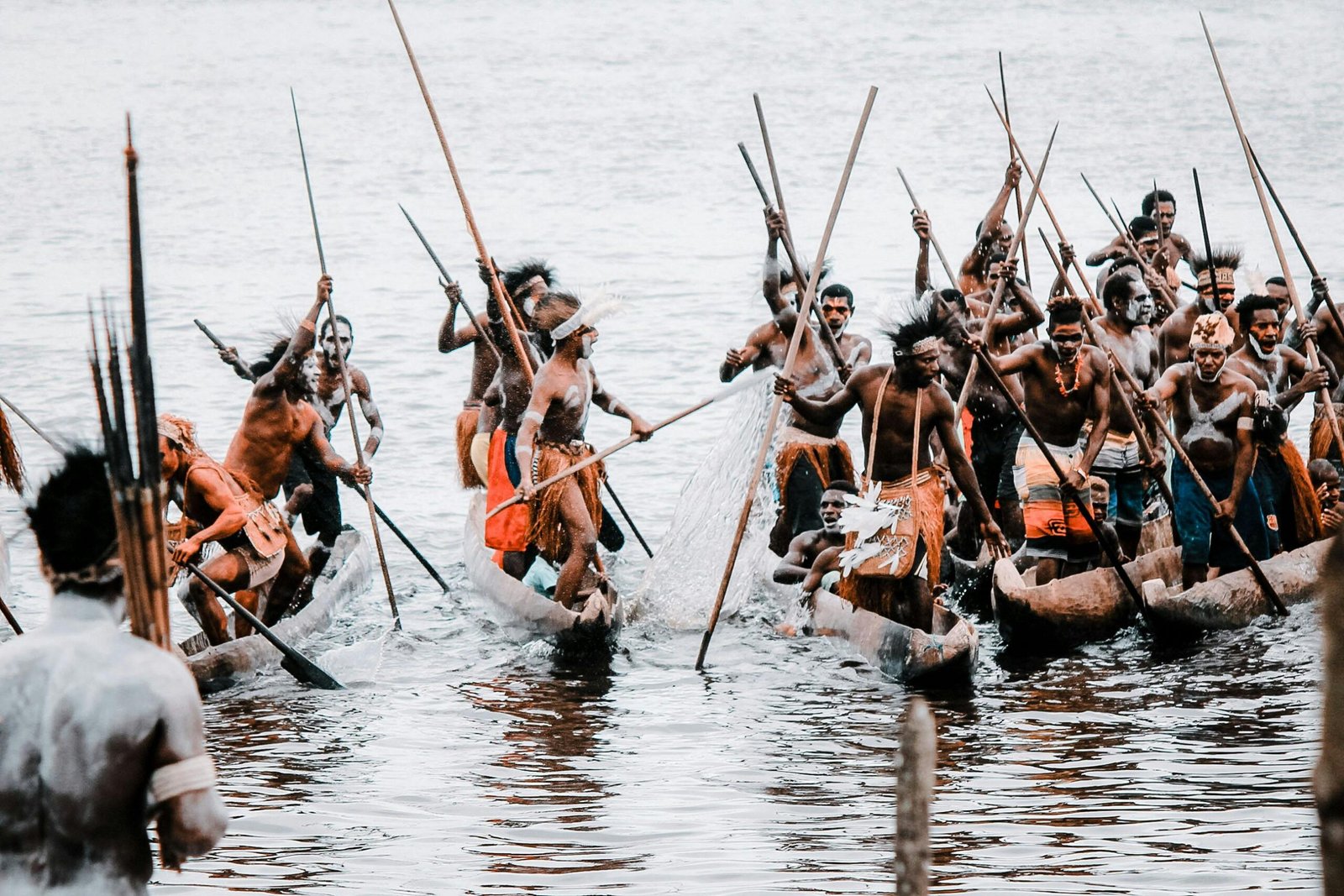 Indigenous tribes in Papua, Indonesia, engaged in a traditional canoe race on a serene water body.