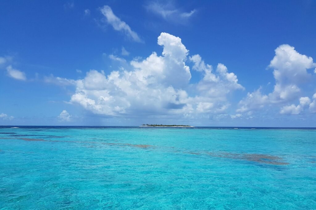 Scenic view of bright turquoise sea with fluffy clouds on a tranquil day.