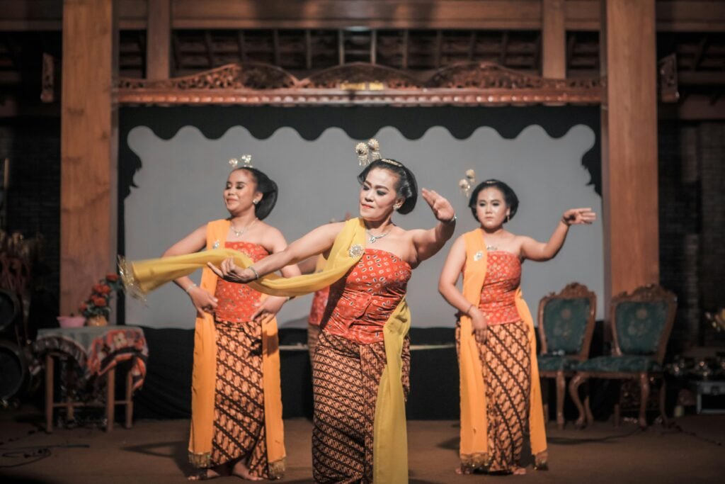 Three women performing a traditional Javanese dance in vibrant costumes on stage.