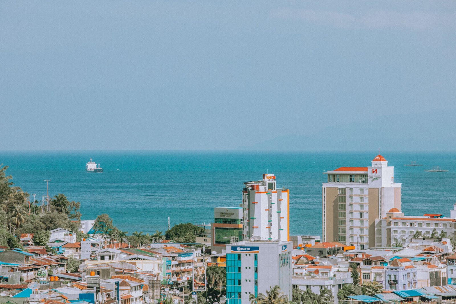 A beautiful coastal view of Jayapura city with high-rise buildings and the ocean horizon.
